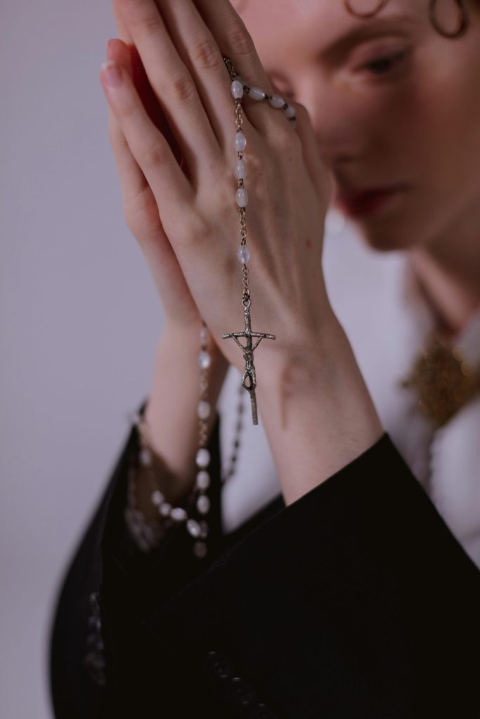 A serene close-up of hands clasped in prayer with a rosary, symbolizing faith and devotion.