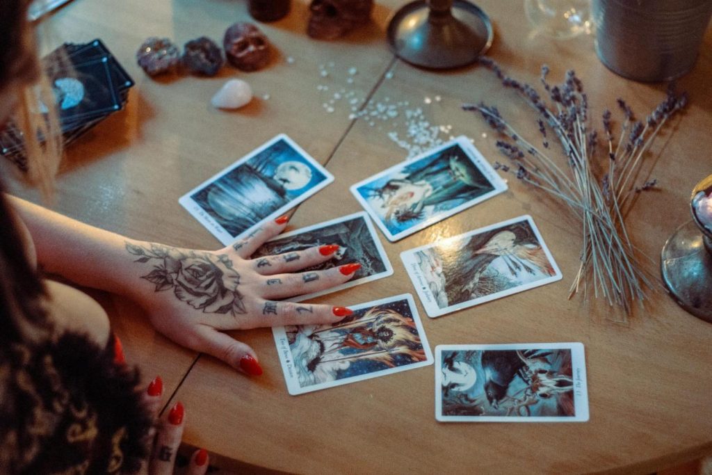 Hand with tattoos arranging tarot cards.