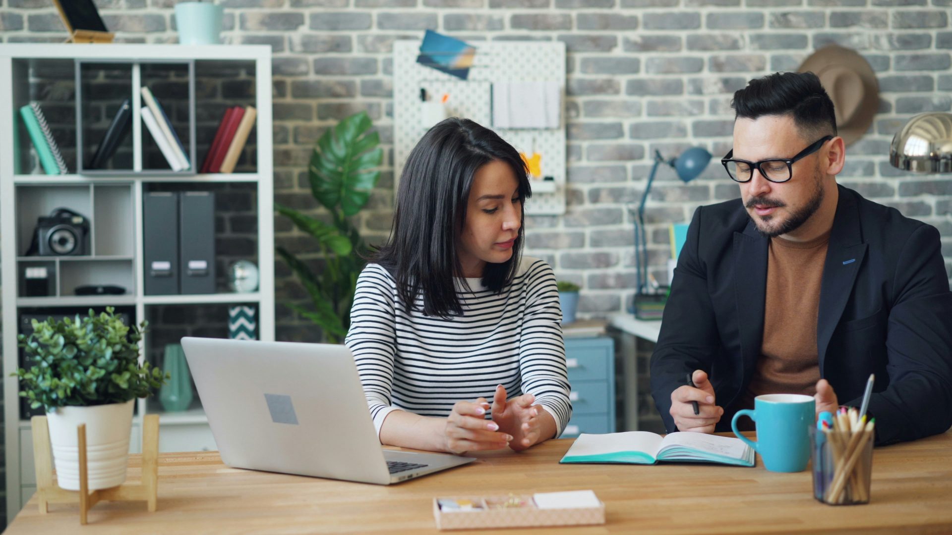 Man and woman studying book at workspace.