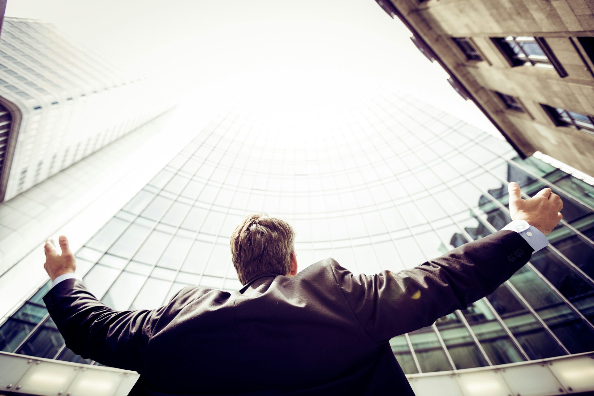 Man raising arms in front of skyscraper
